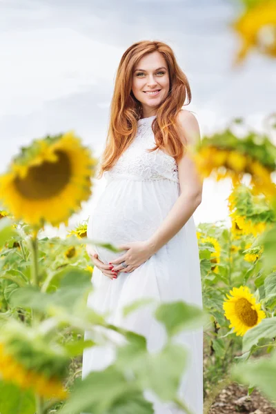 Gravid jente på åkeren med solsikker. – stockfoto