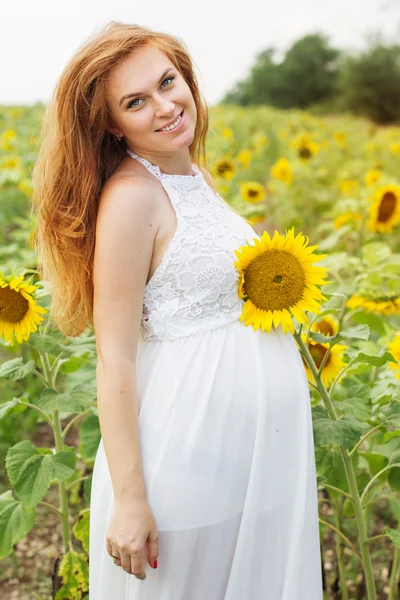 Schwangere auf dem Feld mit Sonnenblumen — Stockfoto