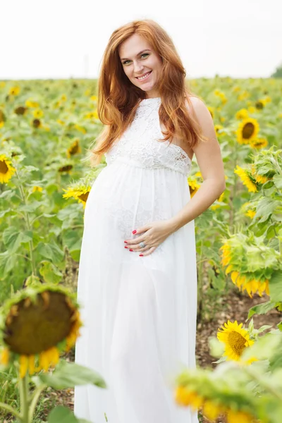 Gravid jente på åkeren med solsikker. – stockfoto