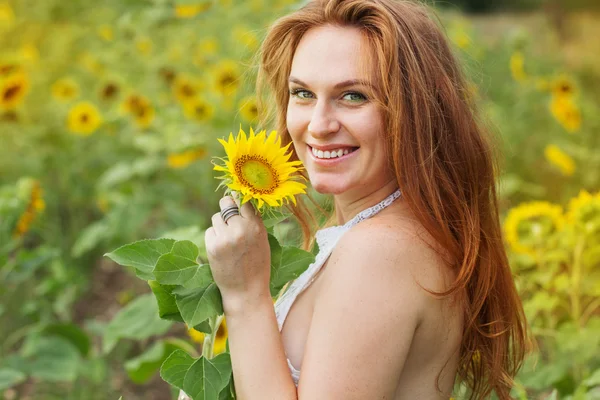 Gelukkige vrouw in het veld met zonnebloemen — Stockfoto