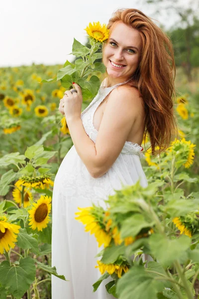 Zwangere vrouw in het veld met zonnebloemen — Stockfoto