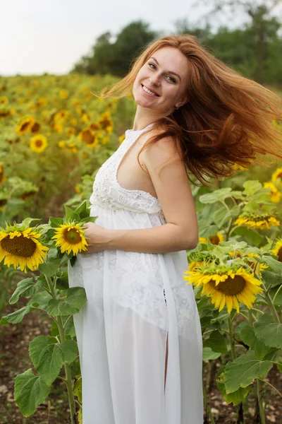 Schwangere auf dem Feld mit Sonnenblumen — Stockfoto