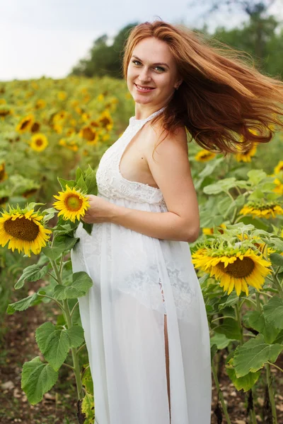 Schwangere auf dem Feld mit Sonnenblumen — Stockfoto