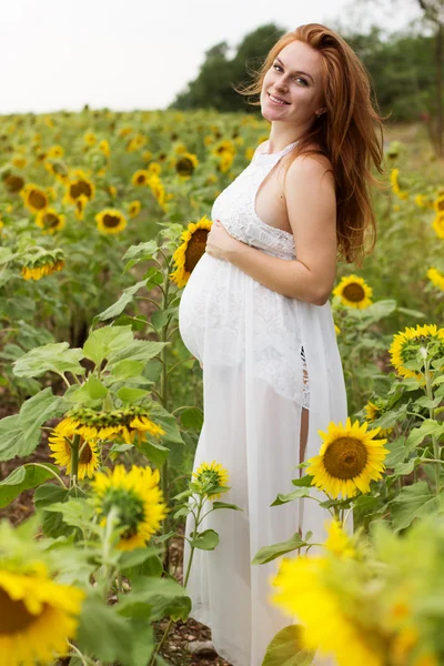 Pregnant happy girl in sunflowers field — Stock Photo, Image