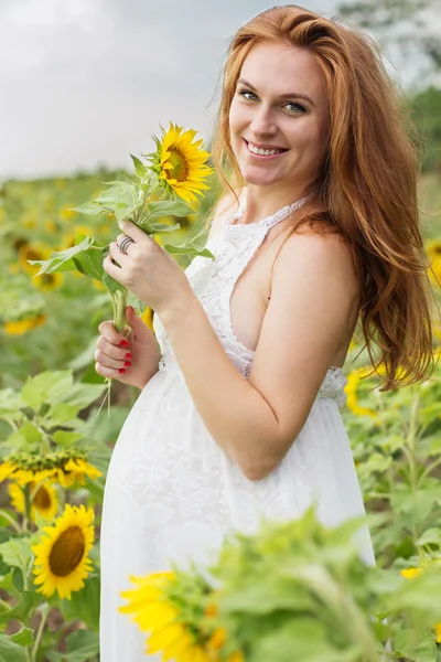 Zwangere gelukkig meisje in zonnebloemen veld — Stockfoto