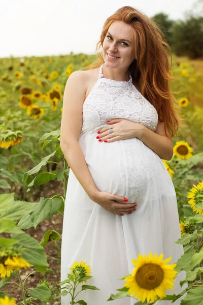 Zwanger meisje in zonnebloemen veld — Stockfoto