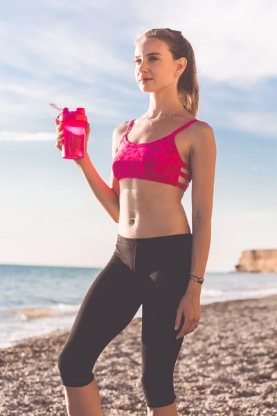 Jovem com garrafa rosa na praia — Fotografia de Stock
