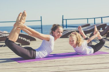 Anne ve kız açık havada yoga yaparken