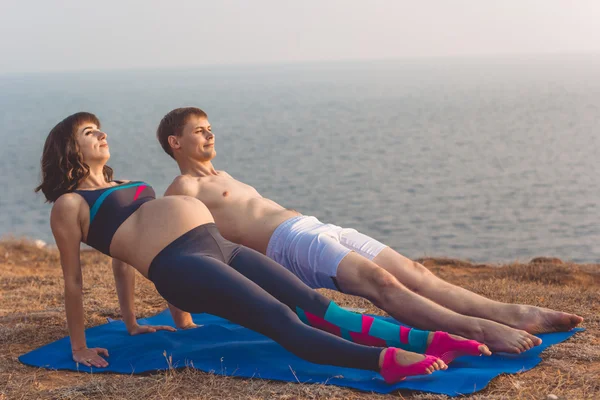 Hombre y esposa embarazada están haciendo deportes en la playa —  Fotos de Stock