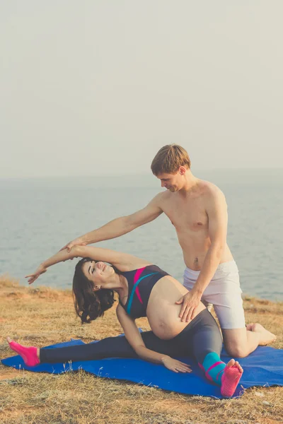 Pregnant girl and man are doing stretching — Stock Photo, Image