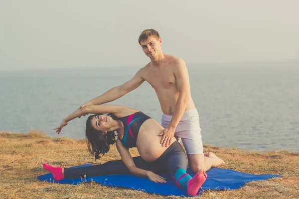Pregnant girl and man are doing stretching — Stock Photo, Image