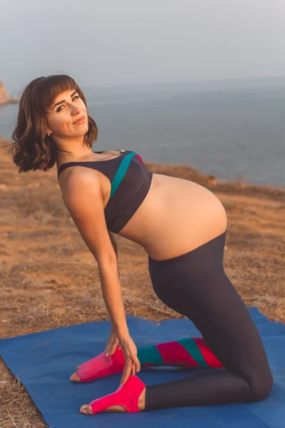 Deportiva embarazada haciendo yoga al aire libre — Foto de Stock