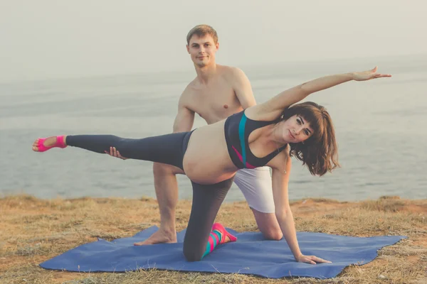 Pregnant girl and man are doing yoga together — Stock Photo, Image