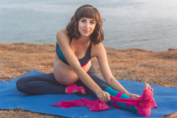 Deportiva embarazada haciendo yoga al aire libre —  Fotos de Stock