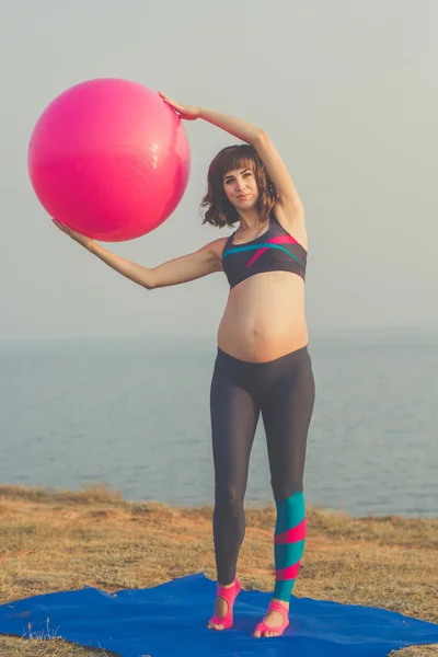 Pregnant girl with pink fitball doing yoga — Stock Photo, Image