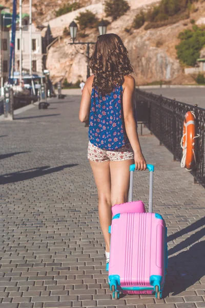 Ładna dziewczyna jest chodzenie z różowy walizka — Zdjęcie stockowe