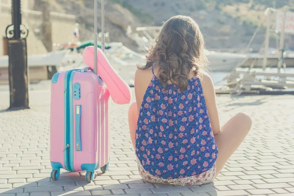 Странница сидит с розовым чемоданом — стоковое фото