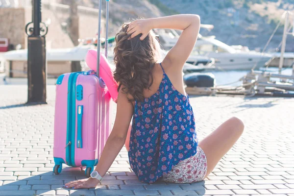 Dziewczyna siedzi z różowy walizka — Zdjęcie stockowe