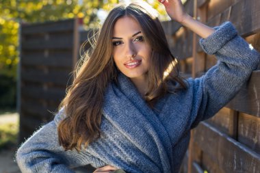 Kız ahşap duvar yakınındaki sıcak giysiler giyiyor