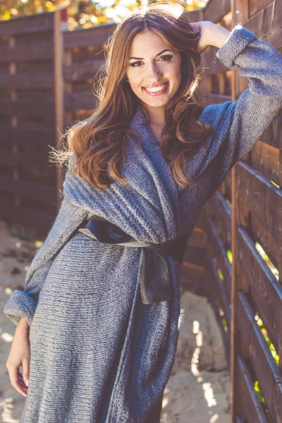 Meisje is het dragen van gebreide kleding in de buurt van houten muur — Stockfoto