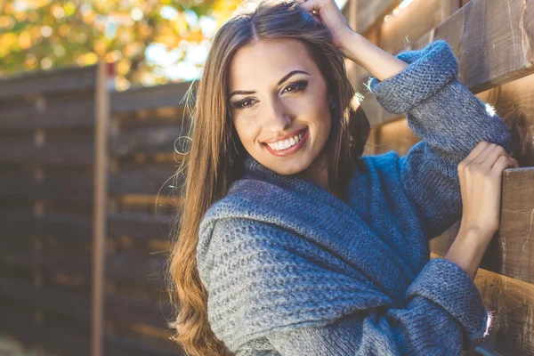 Chica está usando ropa de abrigo cerca de pared de madera —  Fotos de Stock