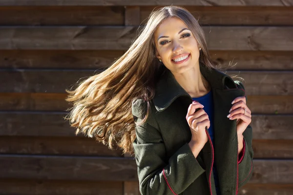 Jolie fille avec des cheveux volants près du mur en bois — Photo