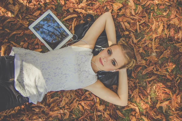 Menina bonita com tablet digital no parque de outono — Fotografia de Stock