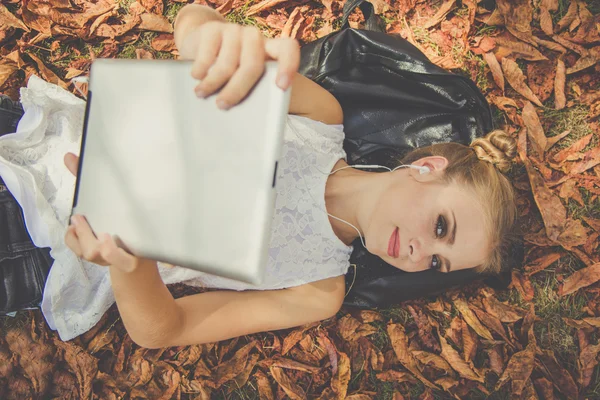 Menina bonita é relaxante com tablet digital ao ar livre — Fotografia de Stock