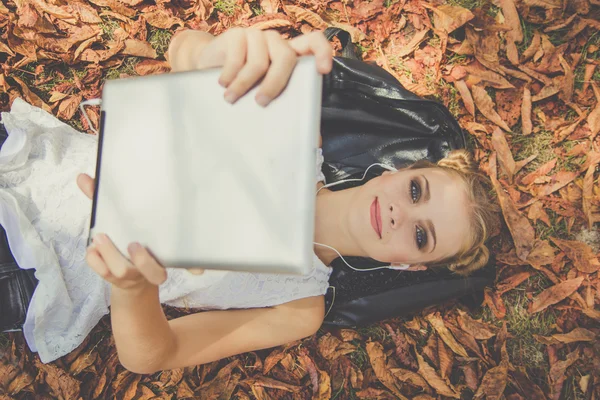 Menina está relaxando com tablet digital ao ar livre — Fotografia de Stock