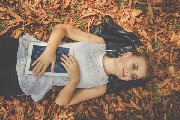 Menina está relaxando com tablet digital ao ar livre — Fotografia de Stock