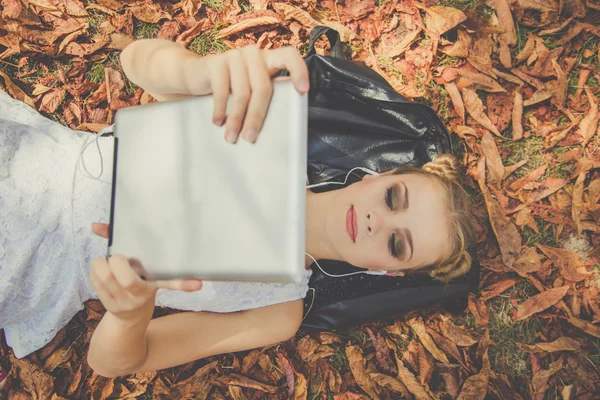 Menina está relaxando com tablet digital ao ar livre — Fotografia de Stock