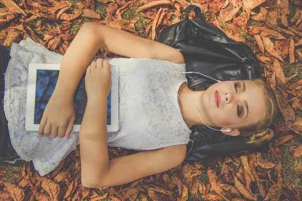 Menina está relaxando com tablet digital ao ar livre — Fotografia de Stock