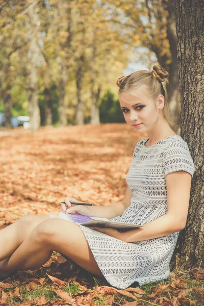 Triste menina adolescente no parque de outono com notebook — Fotografia de Stock