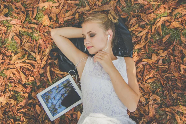 Menina adolescente com tablet digital deitado em folhas — Fotografia de Stock