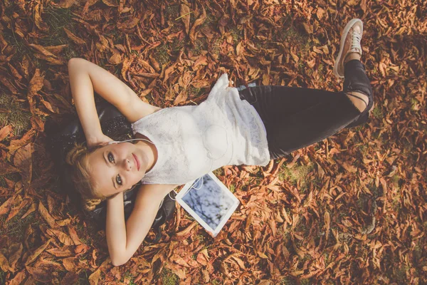 Girl is lying down with digital tablet outdoor — Stock Photo, Image