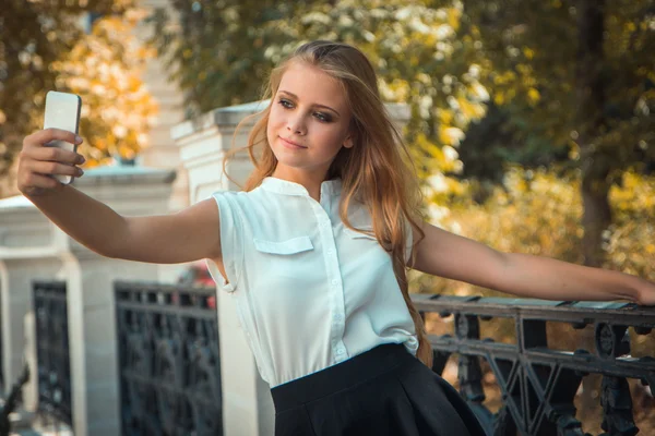Adolescent fille dans automne parc prend selfie — Photo