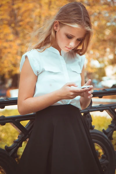 Adolescente dans parc d'automne avec téléphone mobile — Photo