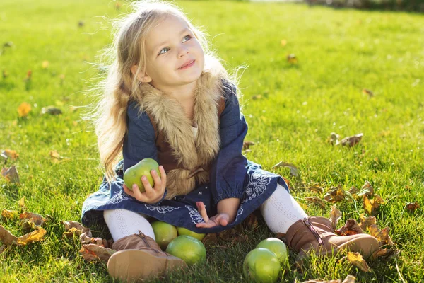 Child with green apples sitting on grass — Stock Photo, Image