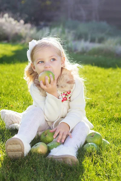 Child with green apples sitting on grass — Stock Photo, Image