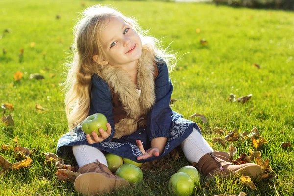 Niño con manzanas verdes sentado en la hierba — Foto de Stock