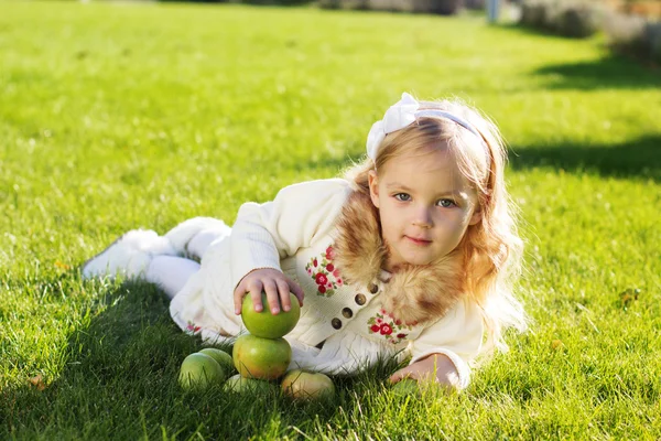 Niño con manzanas verdes sentado en la hierba — Foto de Stock