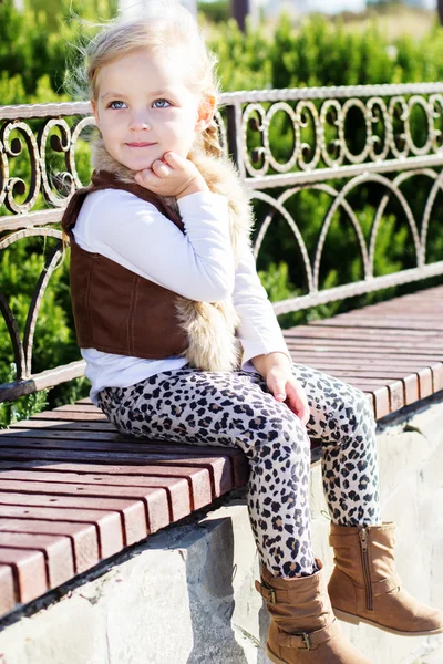 Küçük kız sonbahar bankta oturuyor — Stok fotoğraf