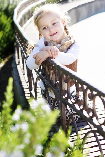 Маленька дівчинка сидить на лавці, осінній час — стокове фото