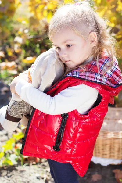 Little girl in warm clothes with toy rabbit — Stock Photo, Image