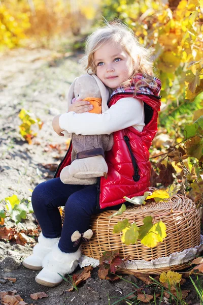 Little girl in warm clothes with toy rabbit — Stock Photo, Image