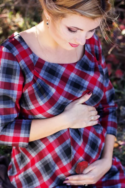 Chica embarazada está usando vestido a cuadros en el parque — Foto de Stock