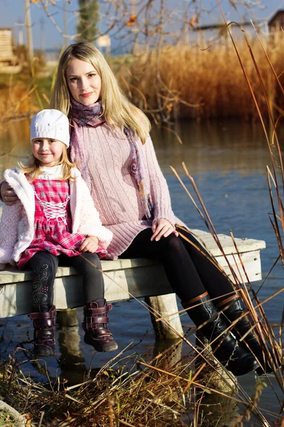 Niña con su madre en el lago de otoño — Foto de Stock