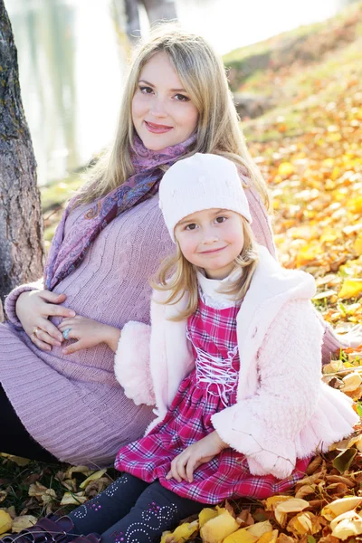 Little girl with her mother on the autumn lake