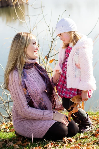 Little girl with her mother on the autumn lake — Stock Photo, Image