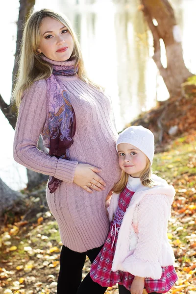 Meisje met haar moeder op de herfst meer — Stockfoto